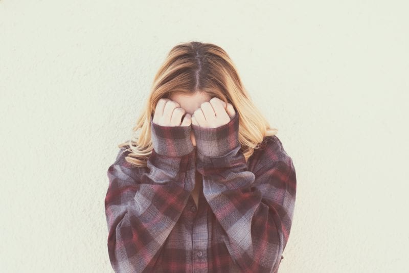 Woman with her face buried in her hands. How to let go of unhealthy guilt.