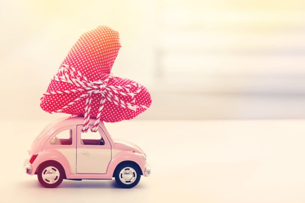 little pink vw bug with a giant heart tied to the top like a tree