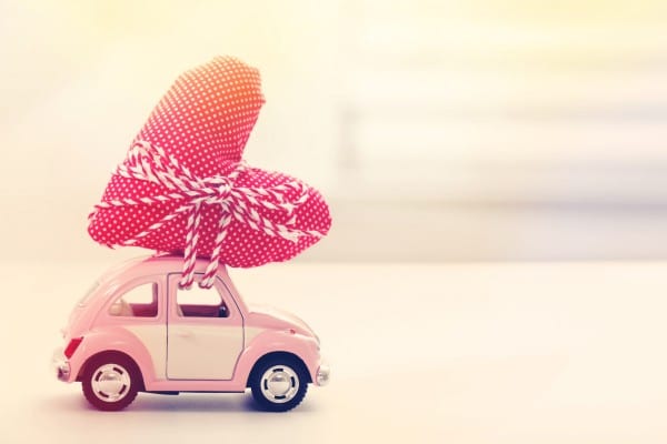 little pink vw bug with a giant heart tied to the top like a tree