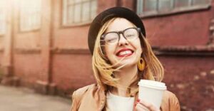 Happy woman with coffee representing The Big Mistake That Can Sabotage Your Happiness.