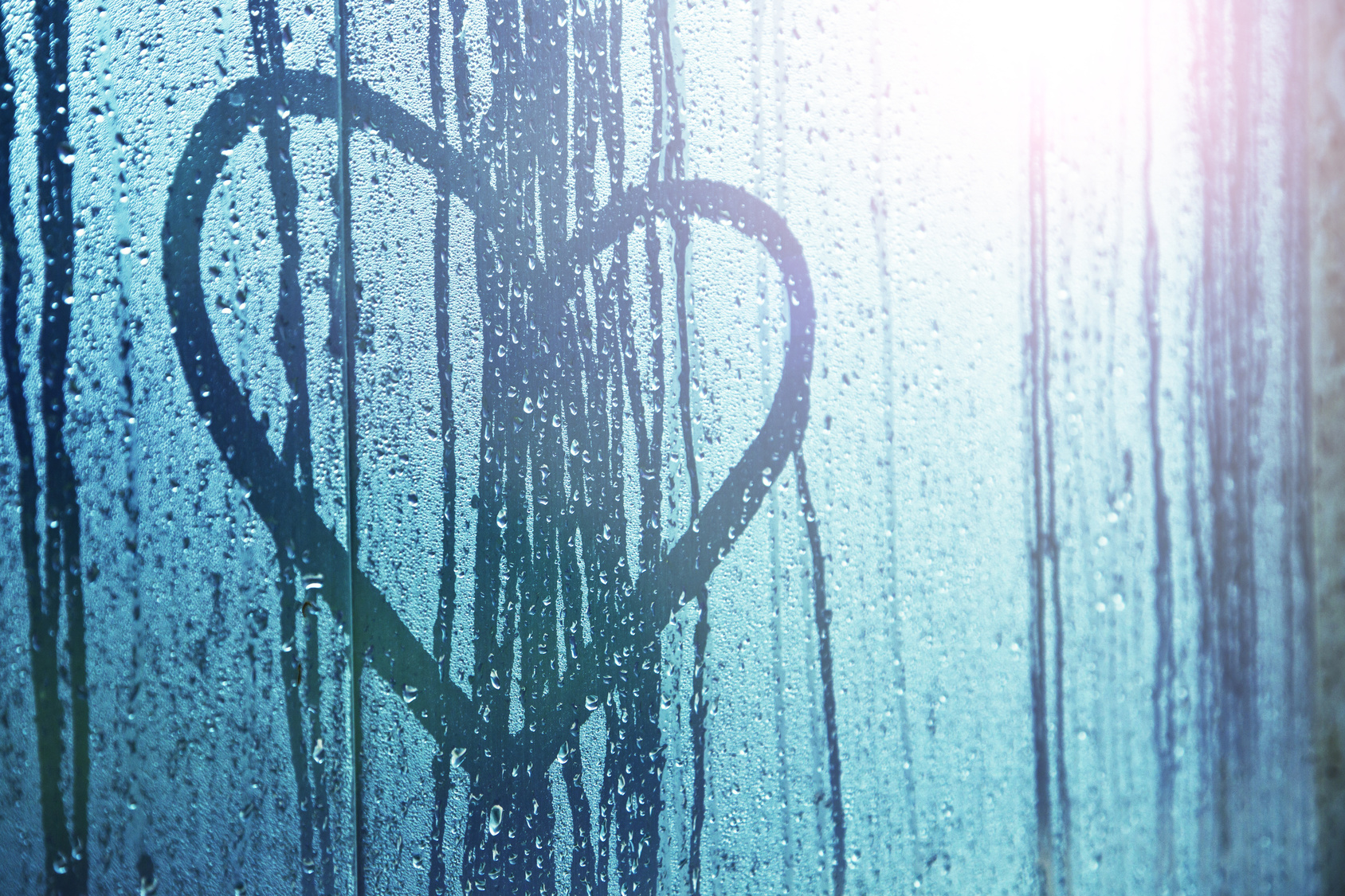 heart drawn on a window, rain dripping down through the heart. How to recover from a breakup.