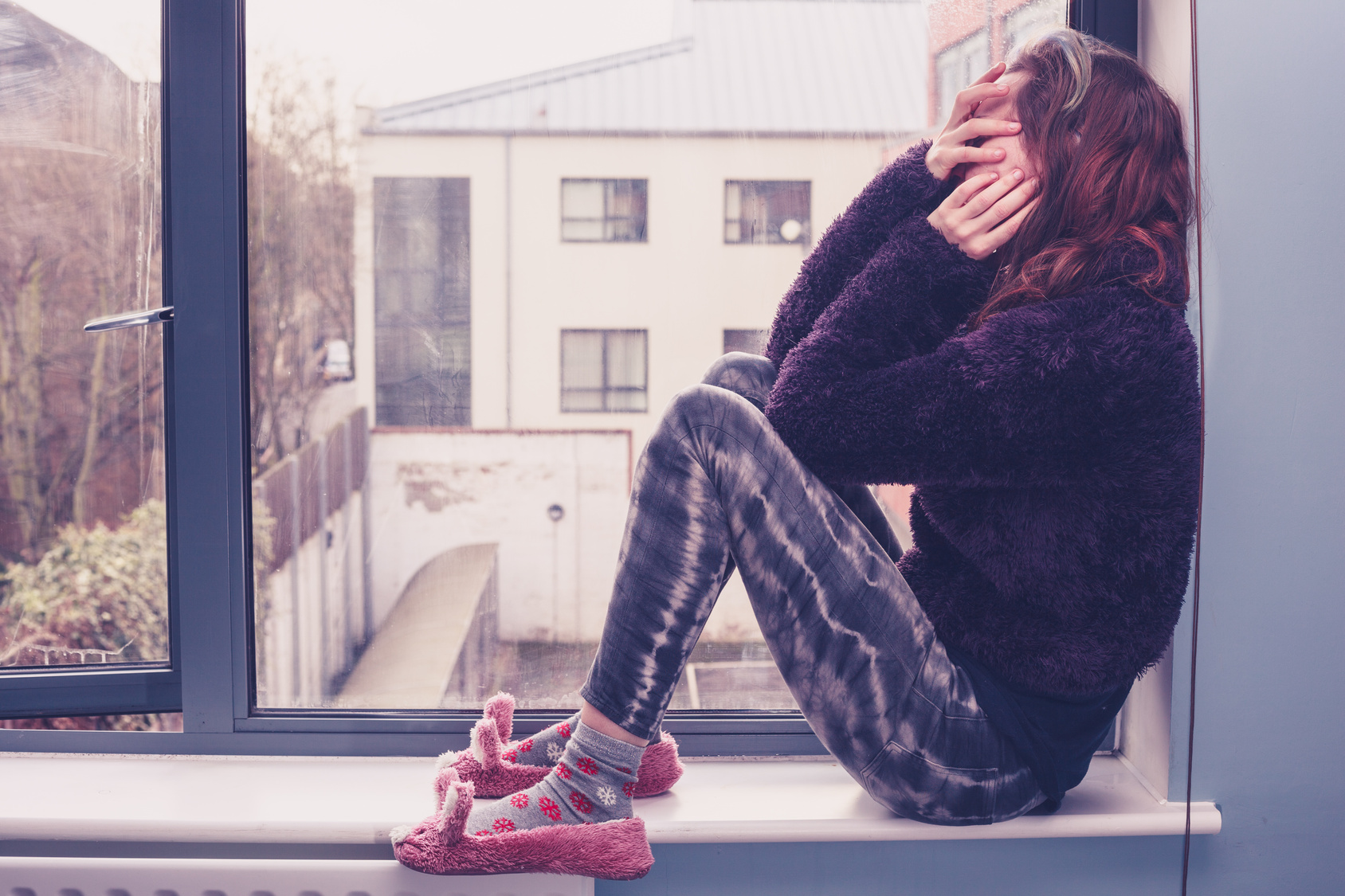 Woman sitting by the window looking sad wondering how to get over it