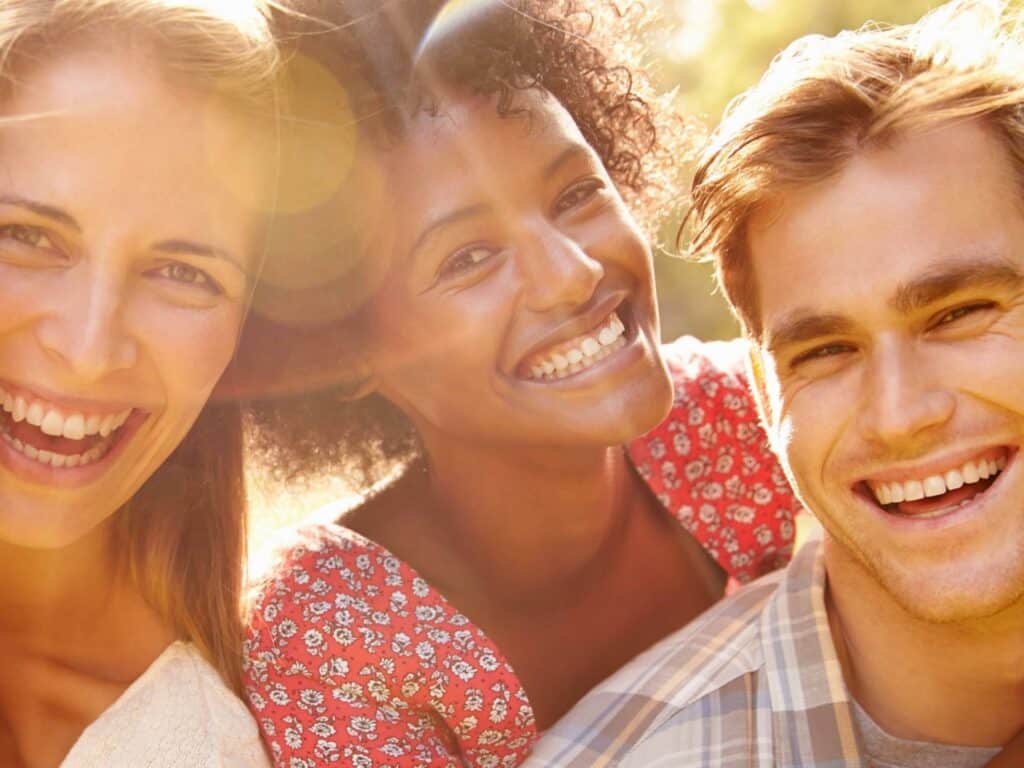 Four friends smiling. Four Secrets of genuinely happy people.
