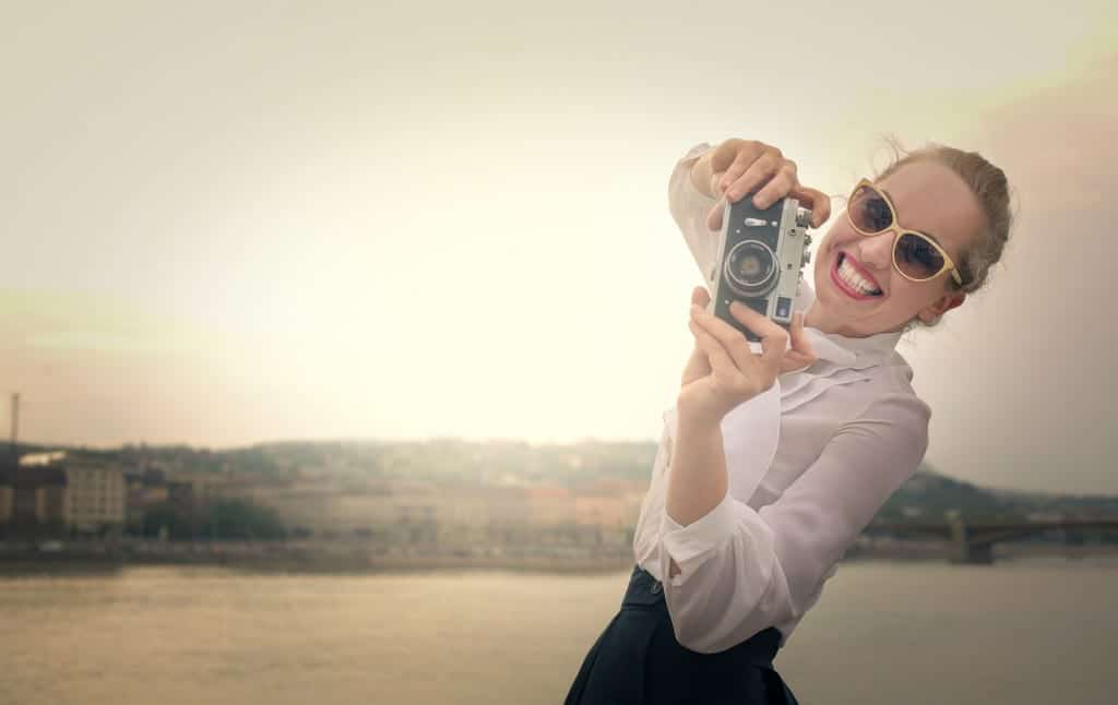 Woman artistically leaning to her side with camera smiling representing How to Get the Best Online Dating Profile Photo