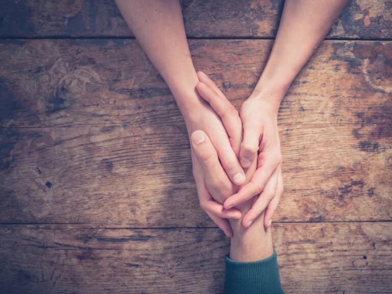 two people's hands clasped. Do you need help? do it right.