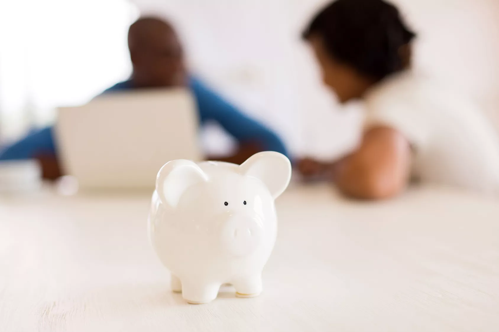 couples talking about financial counseling with couples with a piggy bank on the table.