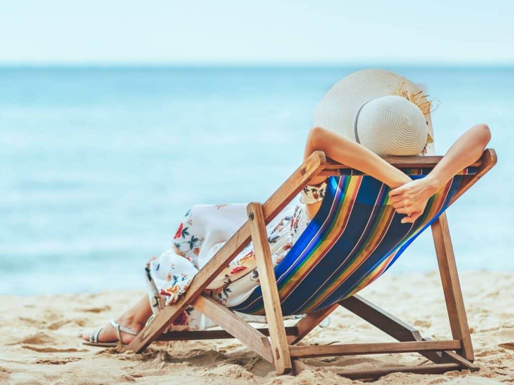 Woman sitting on the beach enjoying restorative vacations