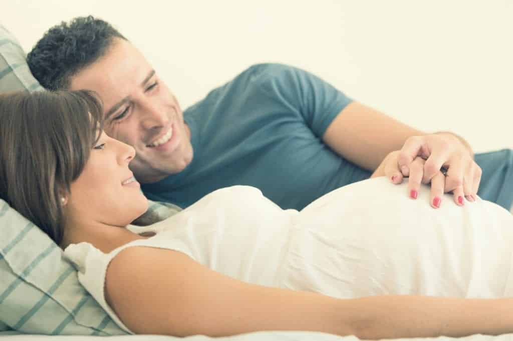 Expecting couple smiling and looking and woman's growing belly preparing to nourish their marriage after kids