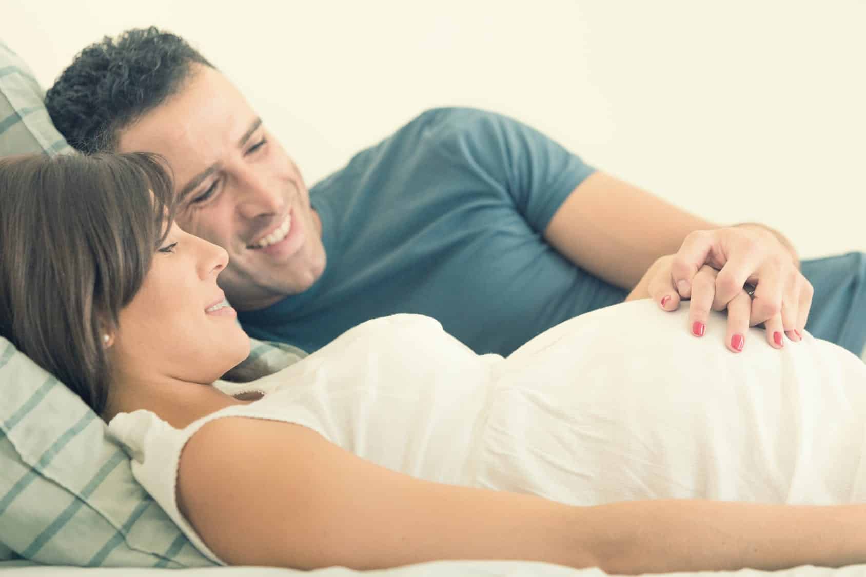 Expecting couple smiling and looking and woman's growing belly preparing to nourish their marriage after kids