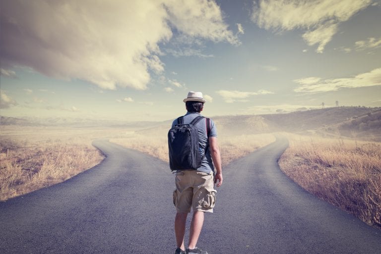 Man walking up to diverging paths wondering whether to follow his head or heart