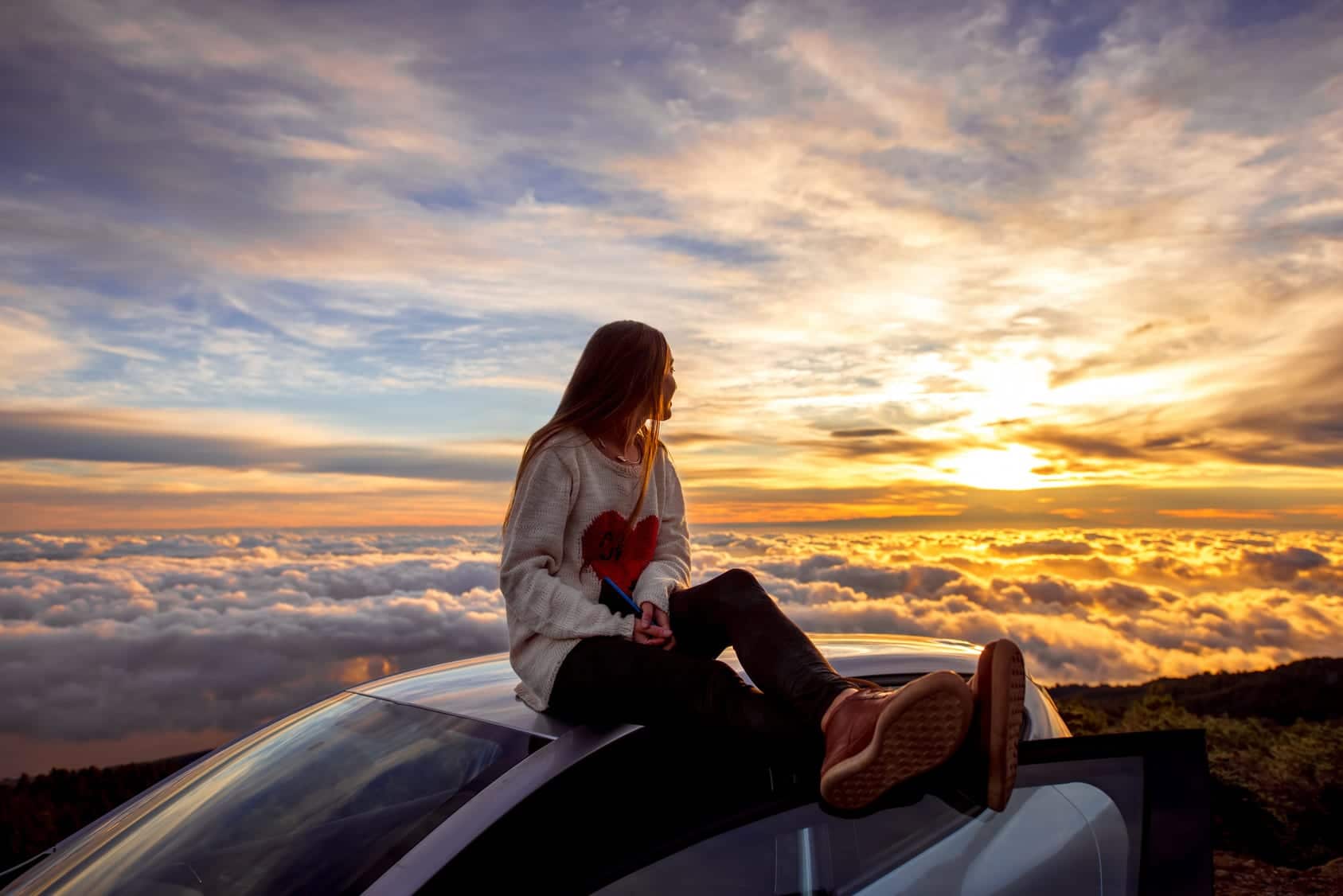 woman on top of the car enjoying the view of the clouds representing Do You Need Therapy of Coaching?