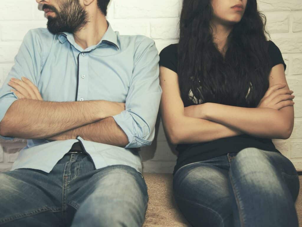 Couple sitting with arms crossed, looking away from each other. How to stop a divorce and save your marriage.