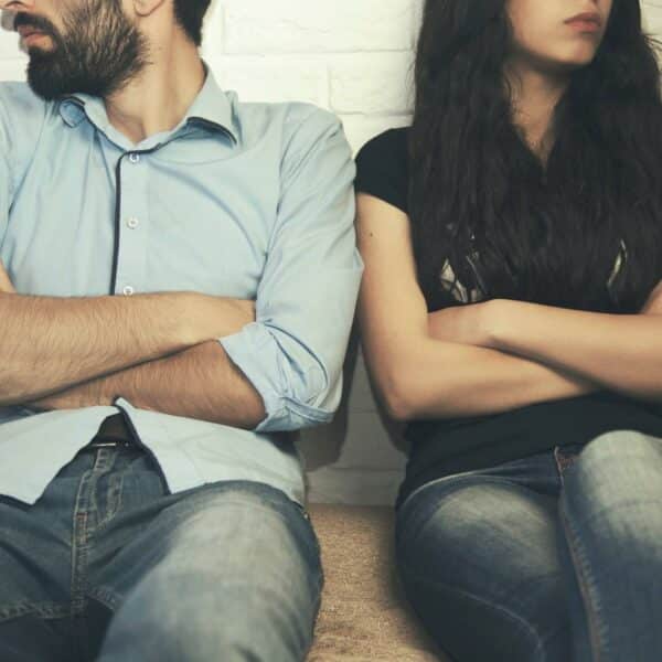 Couple sitting with arms crossed, looking away from each other. How to stop a divorce and save your marriage.