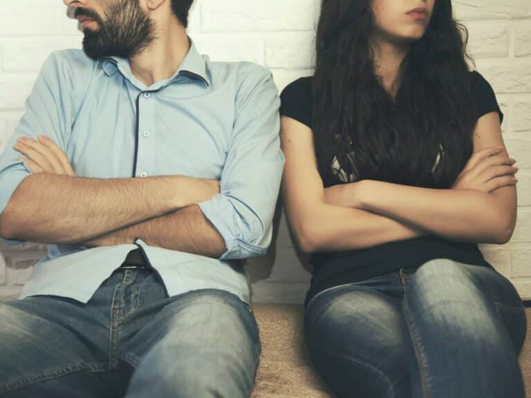 Couple sitting with arms crossed, looking away from each other. How to stop a divorce and save your marriage.