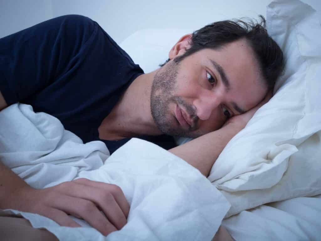 Man in bed, looking sad wondering how do I get over a breakup?