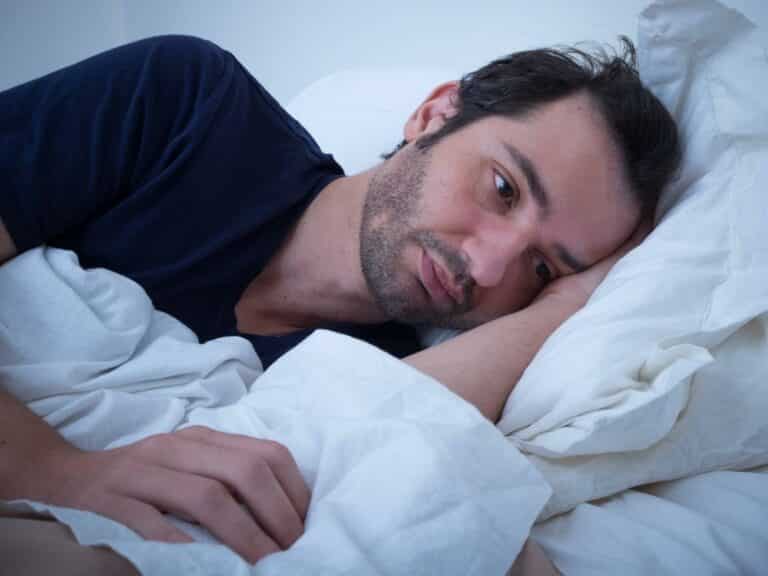 Man in bed, looking sad wondering how do I get over a breakup?