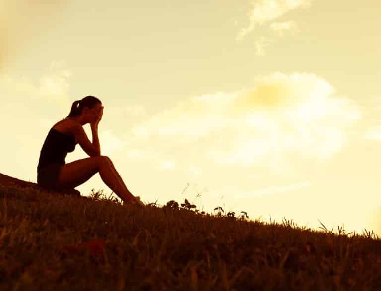 Woman sitting with her face buried in her hands. Getting Over a Breakup: How to Cope With the Pain.