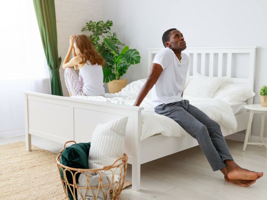 couple sitting at opposite sides of the bed - Is Your Partner Showing Withdrawn Behavior?