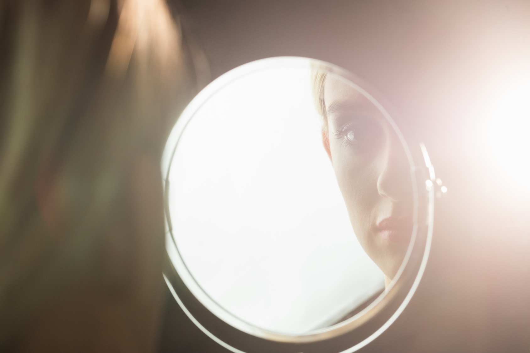 Woman looking into a circular mirror representing Why You Need To Stop Comparing Yourself to Others
