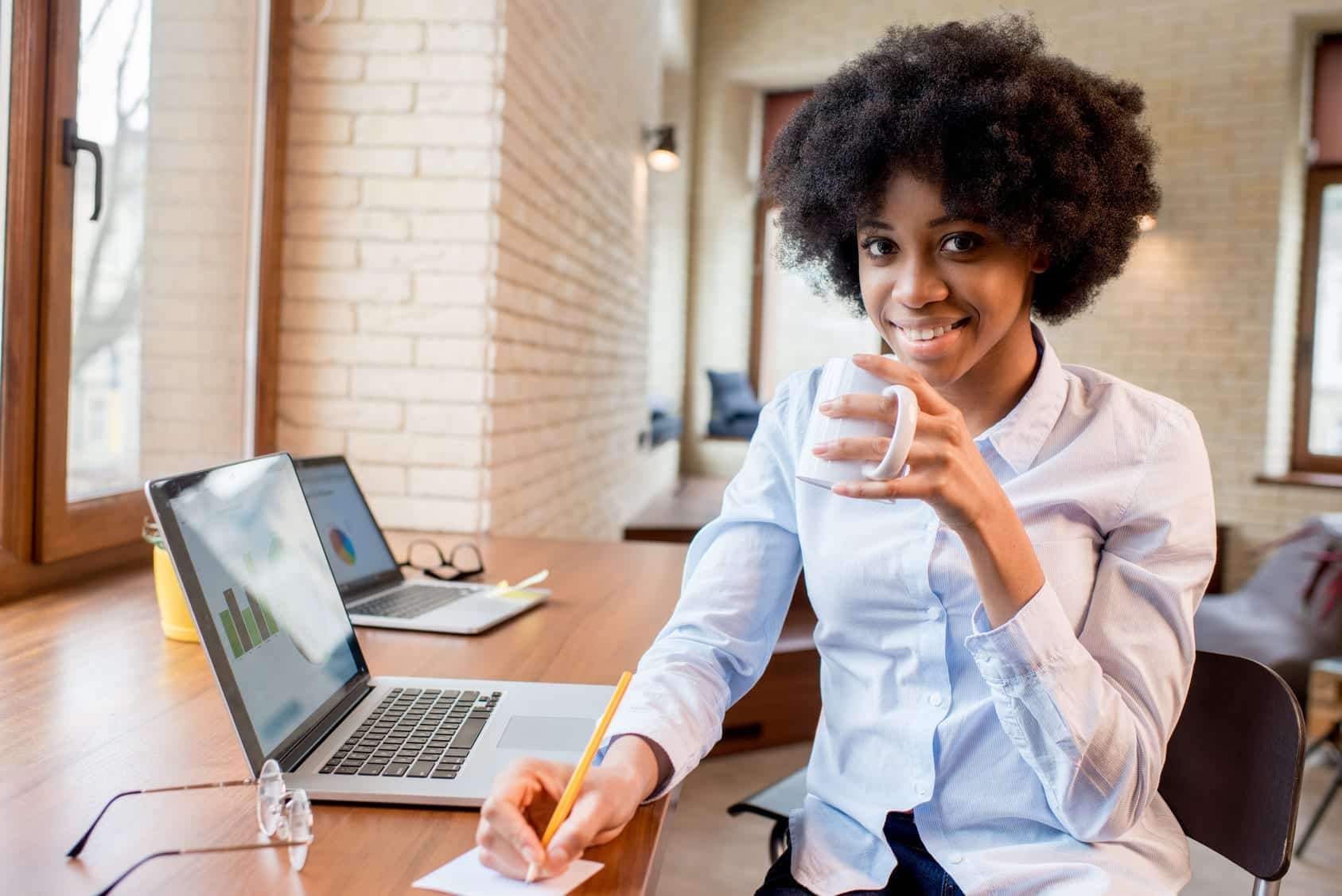 Woman with a successful career sitting at a desk with her laptop and a mug in her hand