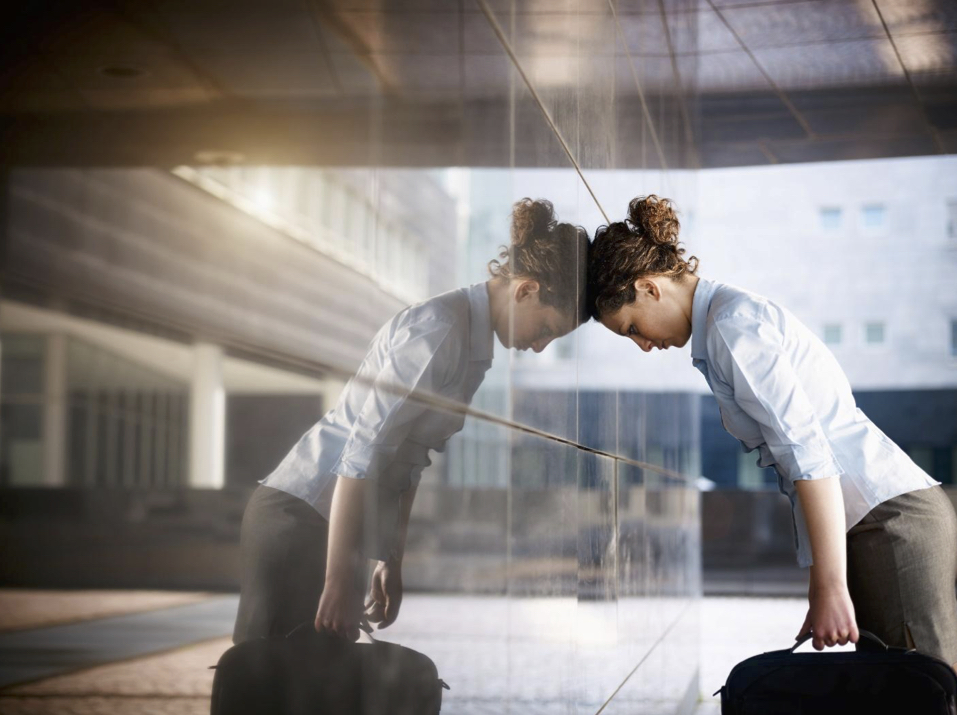 Woman with her head against a wall thinking about leaving a job.