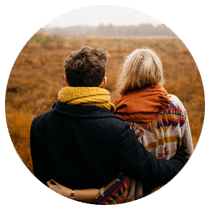 A couple in a healthy relationship, arm in arm, in a fall field.