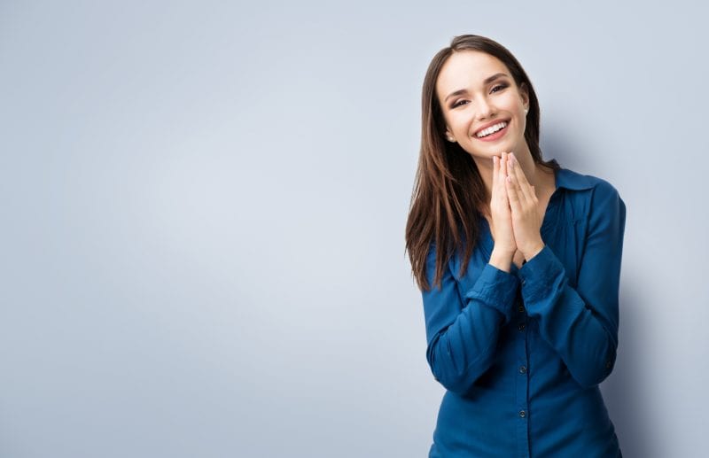 Woman with her hands clasped, looking happy learning how to be her best self