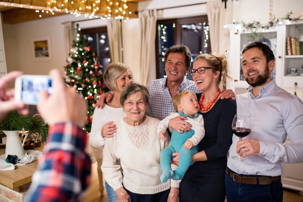 happy multi-generational family taking a holiday picture in front of the christmas tree, representing handle tricky family situations over the holidays
