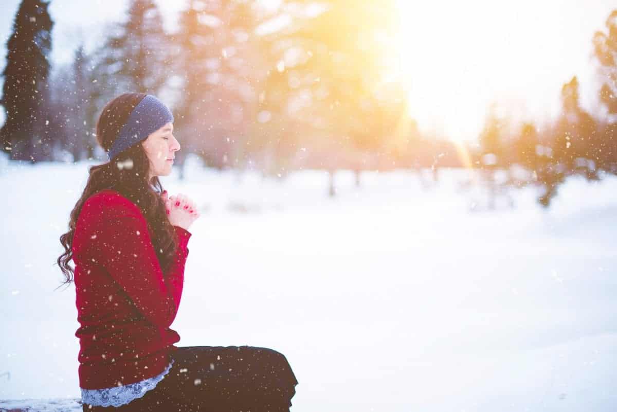 Woman sitting in the snow with her hands together learning how to get out of a funk