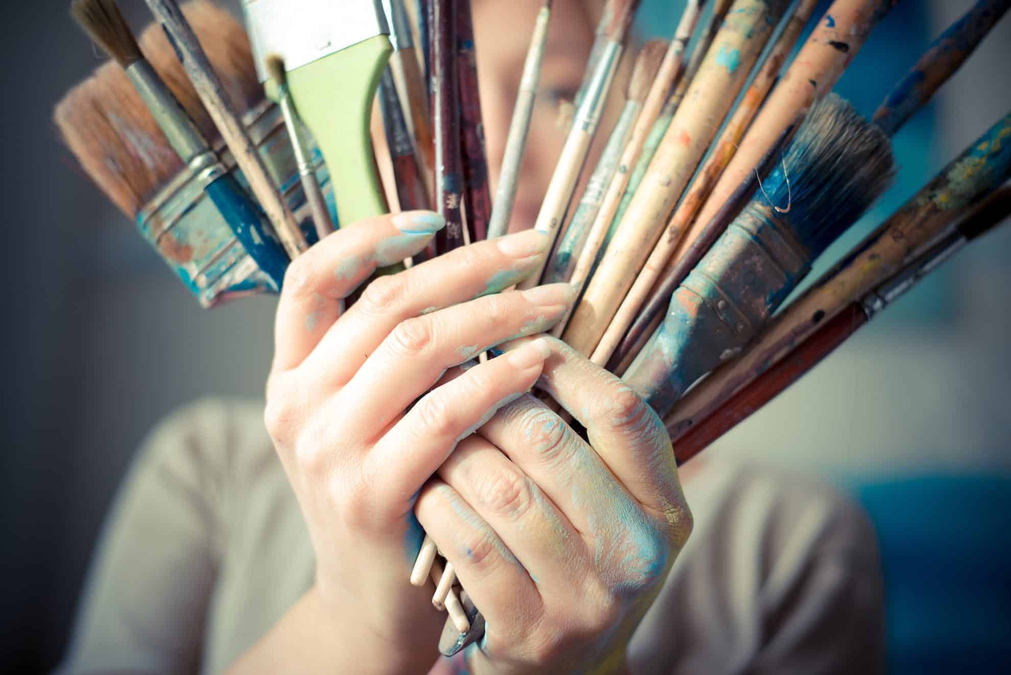 Woman with a creative mind holding a bunch of paintbrushes