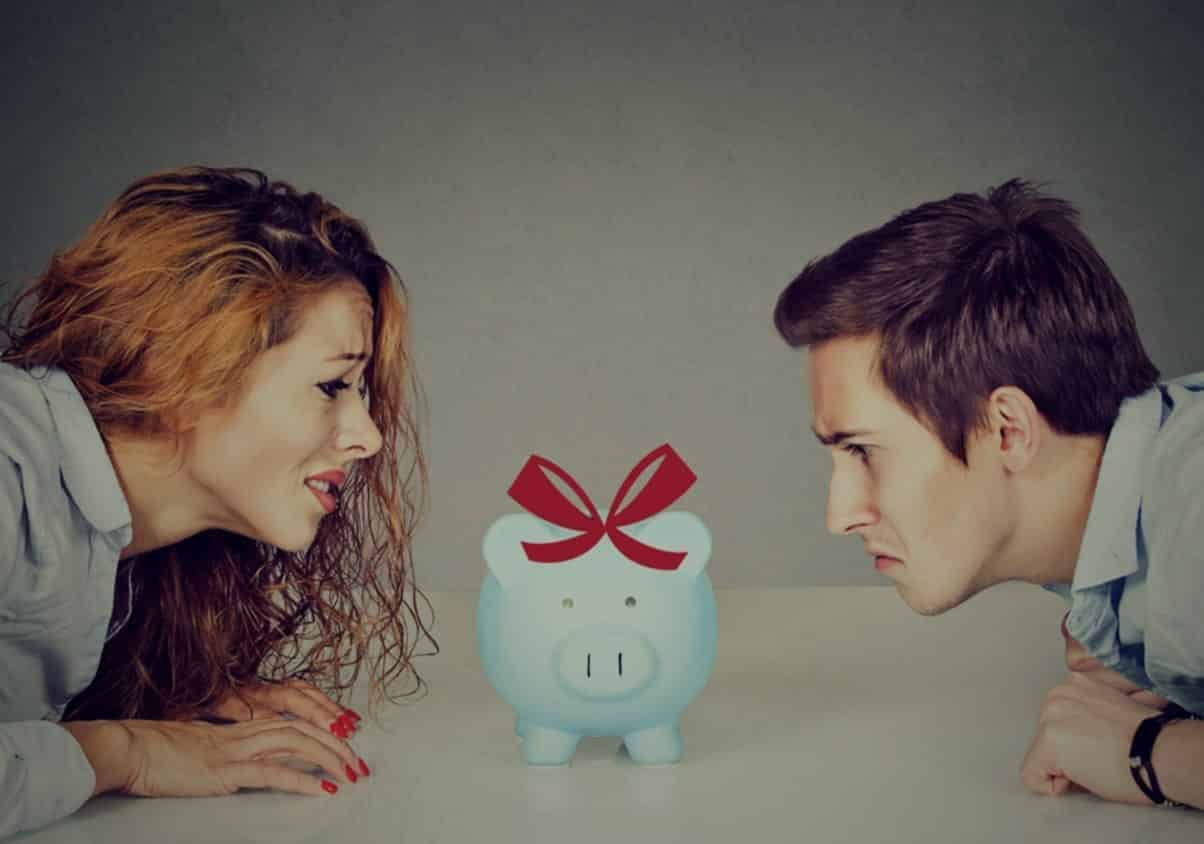 Couple staring at a piggy bank thinking about getting financial therapy for couples