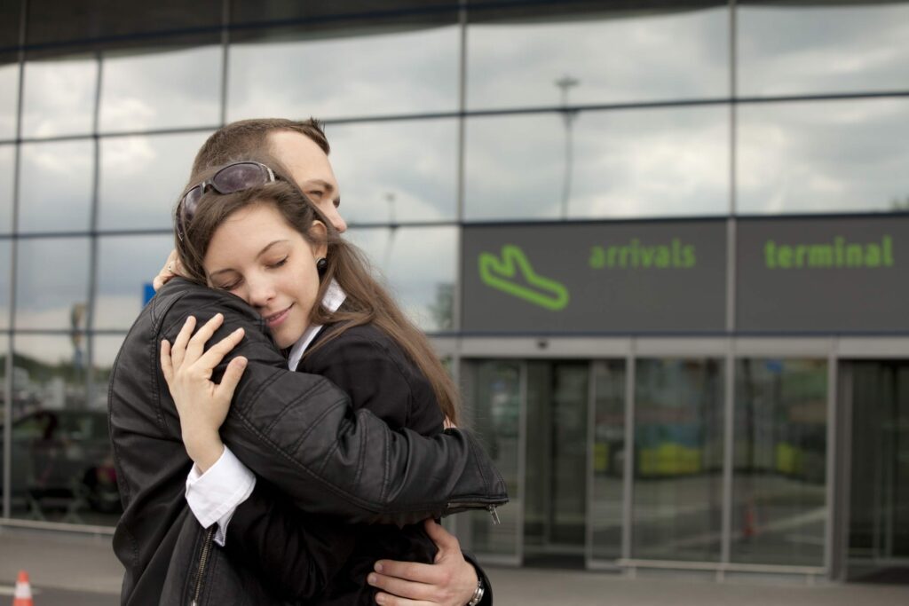 Couple hugging at airport learning How to make long distance work.