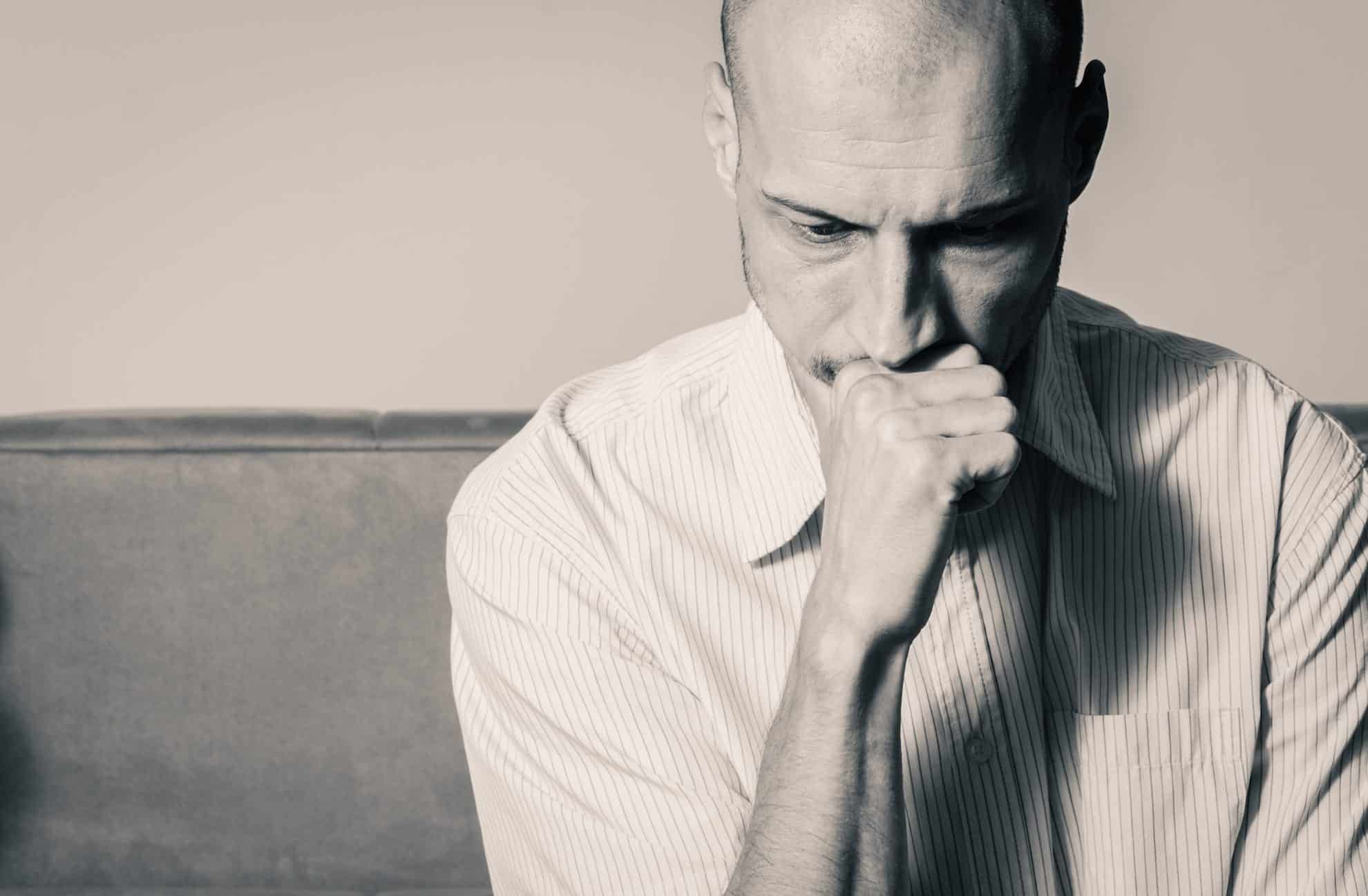 Man sitting with his fist on his chin. How are layoffs like breakups?