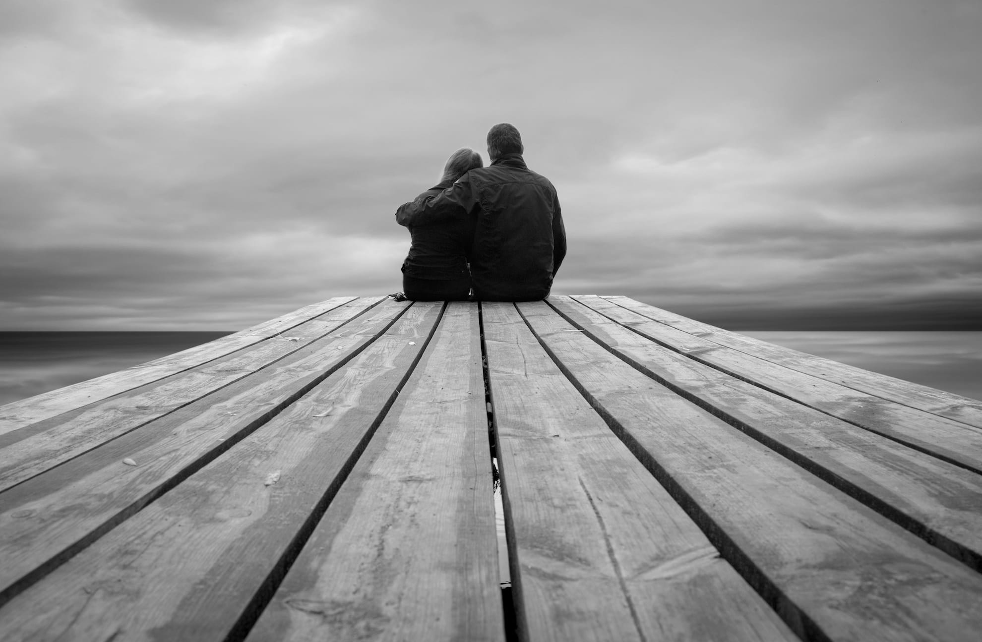 couples sitting on dock holding each other after pregnancy loss