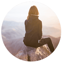 Woman sitting pensively on a mountain.