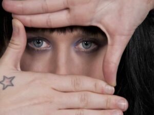 Face hiding behind hands representing How to Be More Vulnerable in Relationships