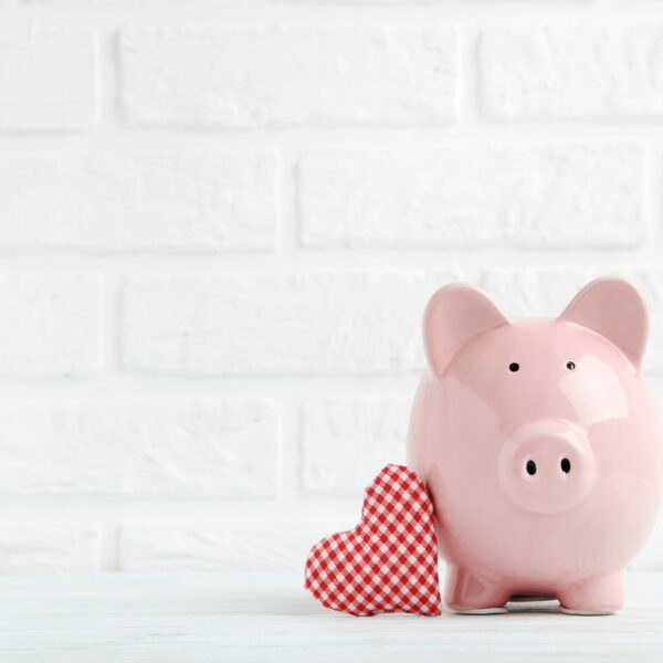 Pink Piggy bank leaning against a plaid heart representing How to Strengthen Your Relationship