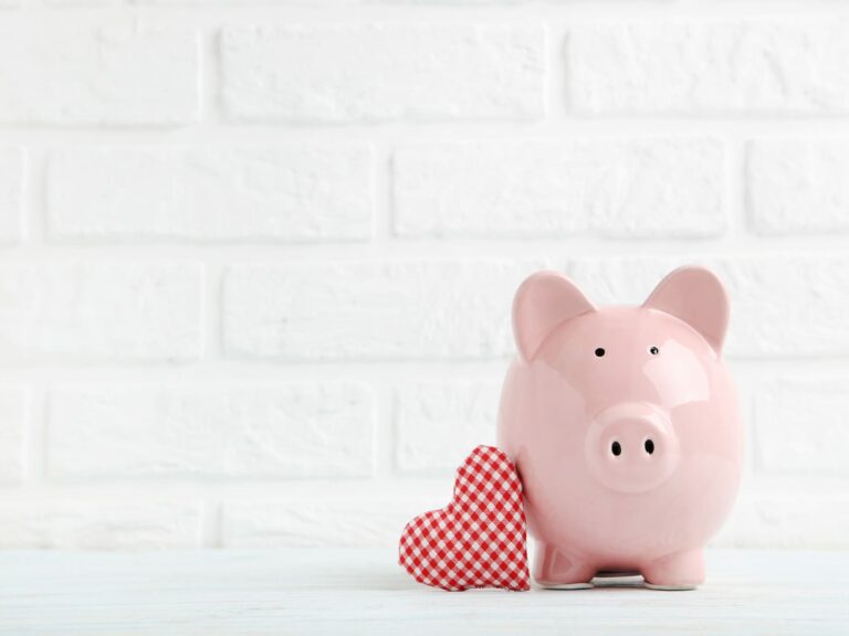 Pink Piggy bank leaning against a plaid heart representing How to Strengthen Your Relationship