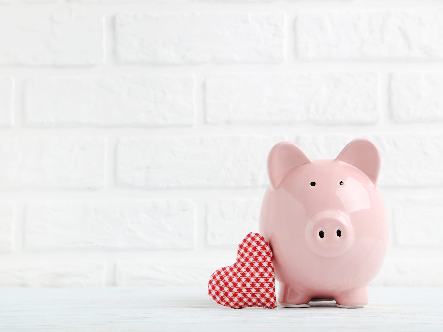 Pink Piggy bank leaning against a plaid heart representing How to Strengthen Your Relationship