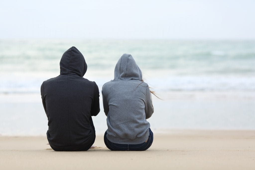 couple sitting on the sand at the beach. Infertility and Pregnancy Loss: How to Heal.