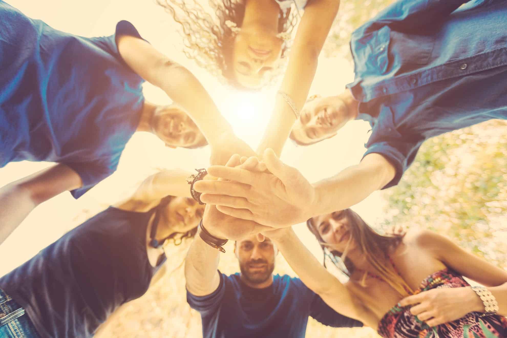 people in a group huddle with everyone's hands in the middle. Why group therapy turbocharges your growth.