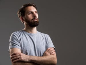 man standing with arms crossed feeling invalidated by his partner