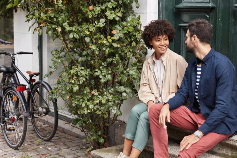 Couple talking on steps outside wondering How to solve relationship problems without breaking up.