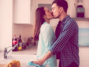 Couple kissing against the kitchen sink. How to Get Your Needs Met in a Relationship.