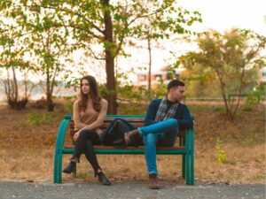 Angry couple sitting on a bench and looking in opposite directions. How to heal a relationship after a fight.