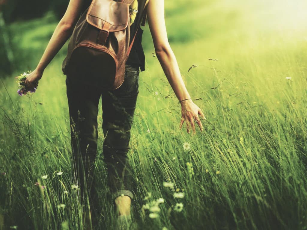 Woman walking through the grass. How to Feel Happier and Less Stressed.