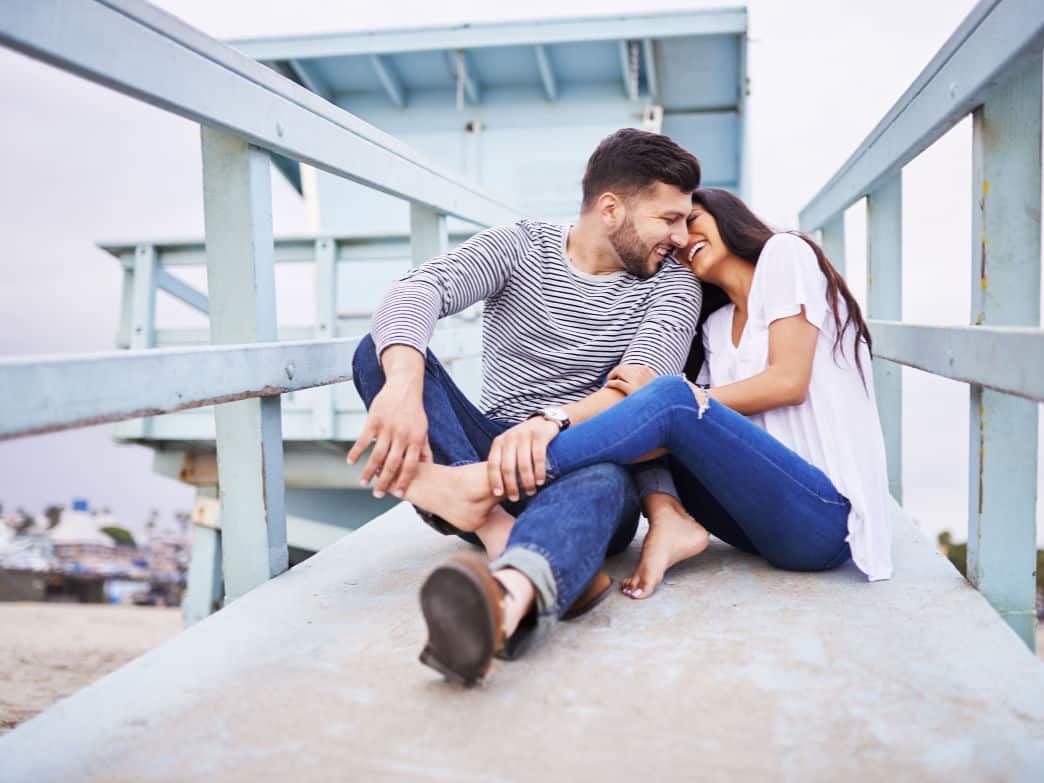 Couple sitting down, embracing on walkway. How to empower your relationship.