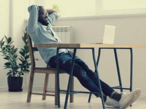 Person sitting back in a chair at a desk. How To Get Ahead At Work.