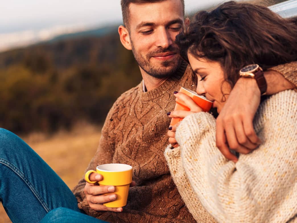 Couple sitting outside with coffee mugs. How to Avoid Unrealistic Expectations.