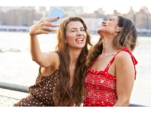 Two girls taking a selfie on the riverfront laughing, representing The Problem with Perfectionism